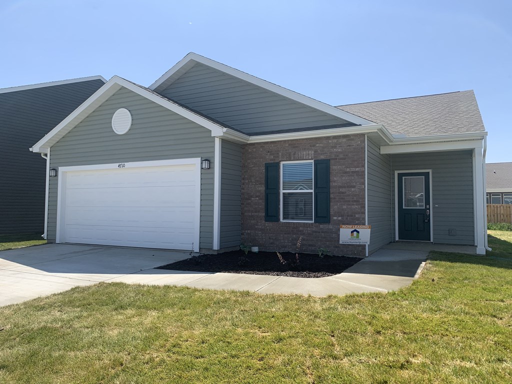 a gray house with a white garage door and a lawn